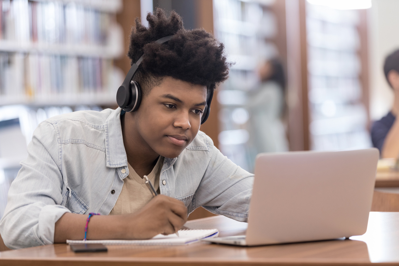 Teen boy uses laptop for homework assignment