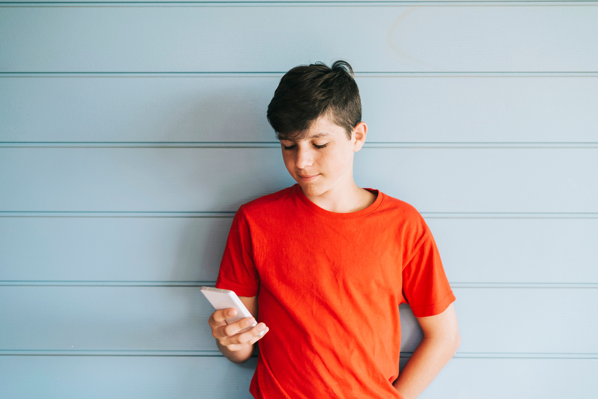 Teen Boy in Orange Shirt Using Smartphone 